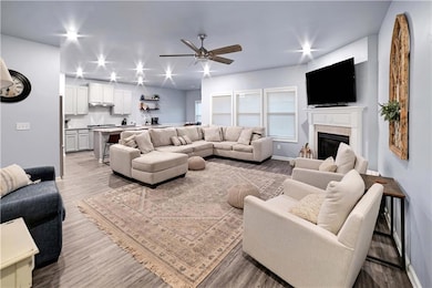 Living area featuring ceiling fan, light wood-style floors, and a glass covered fireplace