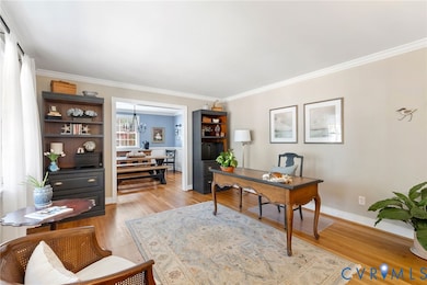 Office area with light wood-style floors, crown molding, and a chandelier