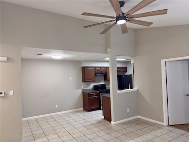 Kitchen featuring stainless steel gas range, freestanding refrigerator, ceiling fan, light tile patterned floors, and under cabinet range hood