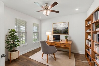 Home office with a ceiling fan, dark wood-type flo