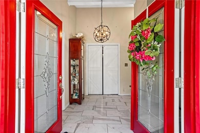 Entrance foyer featuring a chandelier and light marble finish flooring