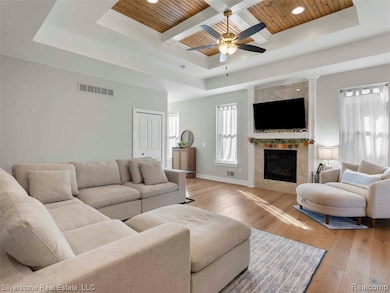 Living room with coffered ceiling, hardwood / wood-style floors, a tray ceiling, a wood ceiling with exposed beams, and a fireplace