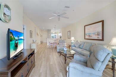 Living room with light wood-type flooring, visible vents, and ceiling fan with notable chandelier