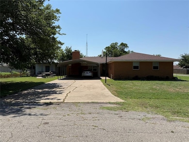 Ranch-style home with concrete driveway, a front lawn, a detached carport, and a chimney