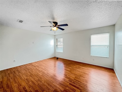 Empty room featuring wood finished floors, a textured ceiling, and ceiling fan