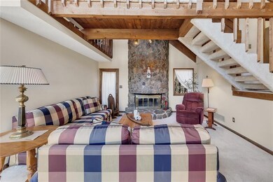 Carpeted living room with a stone fireplace, beame