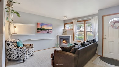 Enter to this spacious, light-filled living room with a wall of windows and cozy electric fireplace. Fireplace is also stubbed for propane.  Attached shelving stays.