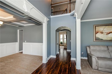 Hall with dark wood finished floors, beamed ceiling, crown molding, coffered ceiling, and arched walkways