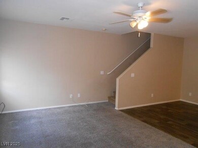 Unfurnished living room featuring a ceiling fan, stairway, dark carpet, and dark wood-type flooring