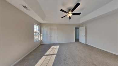 Unfurnished bedroom featuring a raised ceiling, baseboards, carpet flooring, and a closet