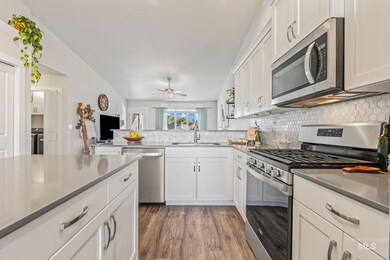 Kitchen featuring stainless steel appliances, white cabinetry, dark wood finished floors, tasteful backsplash, and a ceiling fan