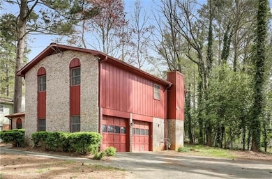View of front of home with brick siding, driveway, a garage, and a chimney