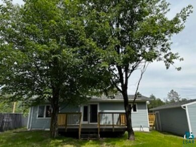 Rear view of house with a lawn and a wooden deck