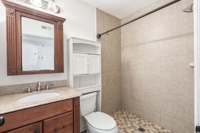 Bathroom with a stall shower, vanity, and toilet