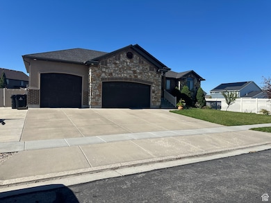 View of front facade with an attached garage, driveway, and stone siding