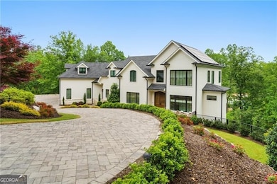French country inspired facade featuring stucco siding, curved driveway, and fence