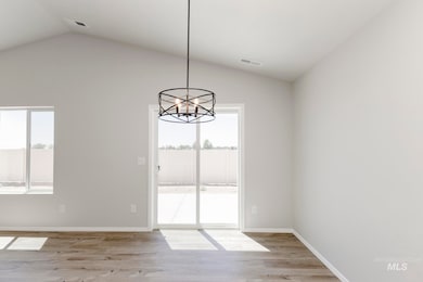 Unfurnished dining area featuring lofted ceiling, light wood-style floors, and a chandelier