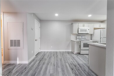 Kitchen with white appliances, white cabinetry, and light hardwood / wood-style flooring