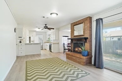 Living room featuring light wood-style flooring, a fireplace, and ceiling fan