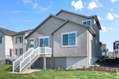Rear view of house featuring a lawn, stucco siding, and central AC