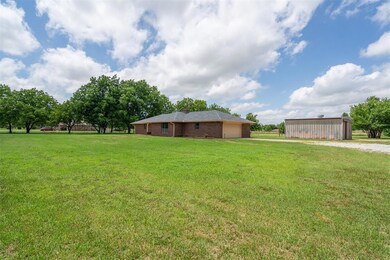 View of green lawn featuring an attached garage, driveway, and an outbuilding