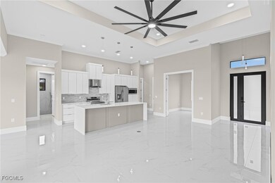 Kitchen with open floor plan, white cabinetry, decorative light fixtures, a kitchen island with sink, and stainless steel appliances