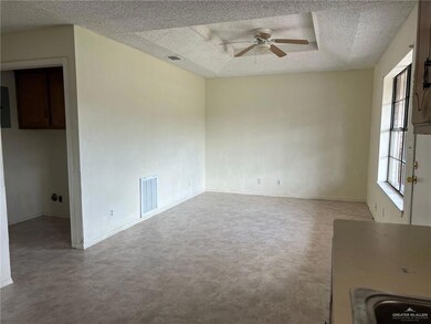 Empty room featuring a textured ceiling, a ceiling fan, and light flooring