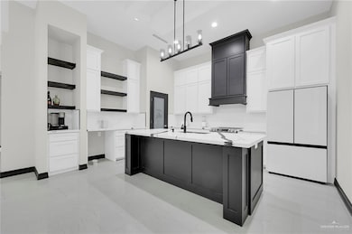 Kitchen featuring open shelves, white fridge, white cabinetry, decorative light fixtures, and a kitchen island with sink