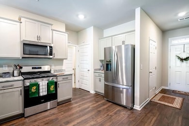Kitchen featuring stainless steel appliances, dark wood finished floors, light stone countertops, and recessed lighting