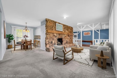 Living area featuring carpet, a chandelier, and a stone fireplace