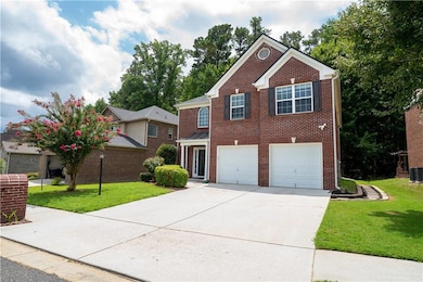 Traditional-style house featuring a front lawn, concrete driveway, an attached garage, and brick siding
