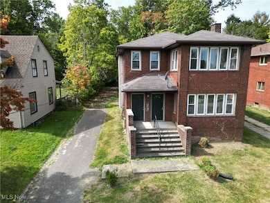 View of front of home with brick siding, a chimney, a front yard, and driveway