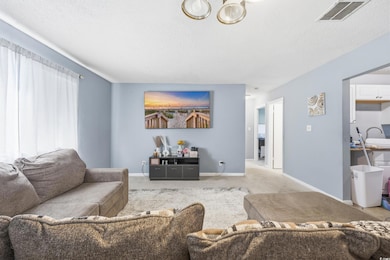 Carpeted living area featuring a textured ceiling and baseboards