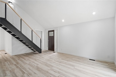Foyer entrance with light wood finished floors, stairway, recessed lighting, and vaulted ceiling