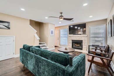 Living area with a stone fireplace, stairway, woo