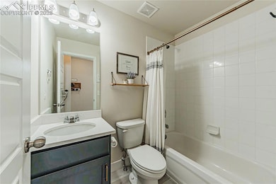 Bathroom with shower / bathtub combination with curtain, vanity, and toilet