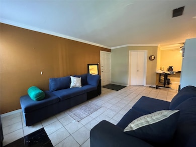 Living area featuring light tile patterned floors and crown molding