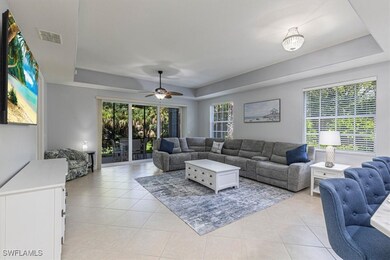 Living room featuring a tray ceiling, light tile patterned floors, a ceiling fan, and healthy amount of natural light