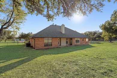 Back of property featuring brick siding, a chimney, a patio area, and a shingled roof