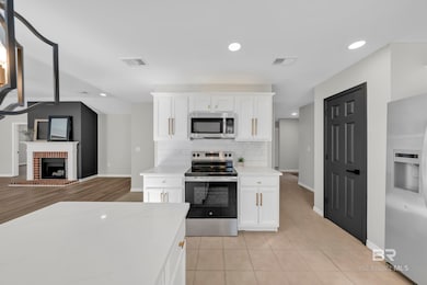 Kitchen with recessed lighting, white cabinets, stainless steel appliances, light stone countertops, and tasteful backsplash