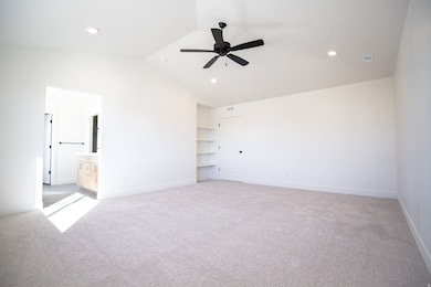 Primary bedroom with vaulted ceiling, ceiling fan and built-in shelves.
