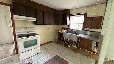 Kitchen with dark brown cabinetry, white electric range, under cabinet range hood, and light tile patterned flooring