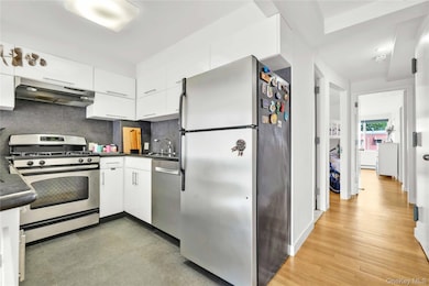 Kitchen with dark countertops, stainless steel appliances, white cabinetry, and tasteful backsplash