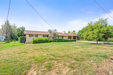 Single story home with an attached garage, a front lawn, driveway, and a chimney