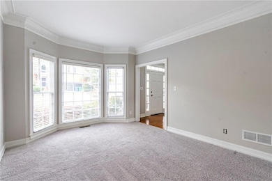 Carpeted spare room featuring crown molding and baseboards