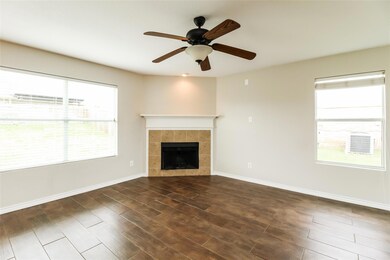 Unfurnished living room featuring ceiling fan, dark wood-type flooring, and a tiled fireplace