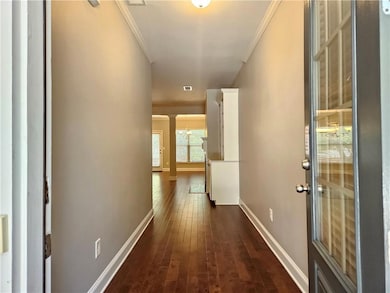 Corridor featuring ornamental molding, baseboards, dark wood-style floors, and a chandelier