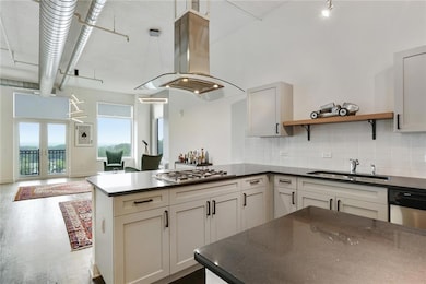Kitchen featuring island exhaust hood, a sink, stainless steel gas stovetop, and dark countertops