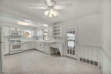 Kitchen with wallpapered walls, white appliances, open shelves, light countertops, and white cabinets