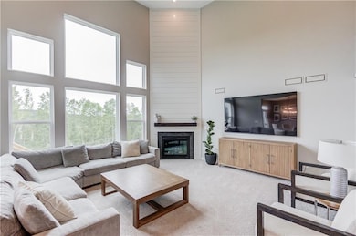 Carpeted living area with a high ceiling and a large fireplace